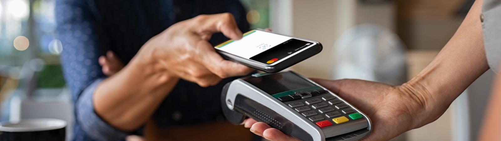 Eine Frau bezahlt im Geschäft mit ihrem iPhone und Apple Pay