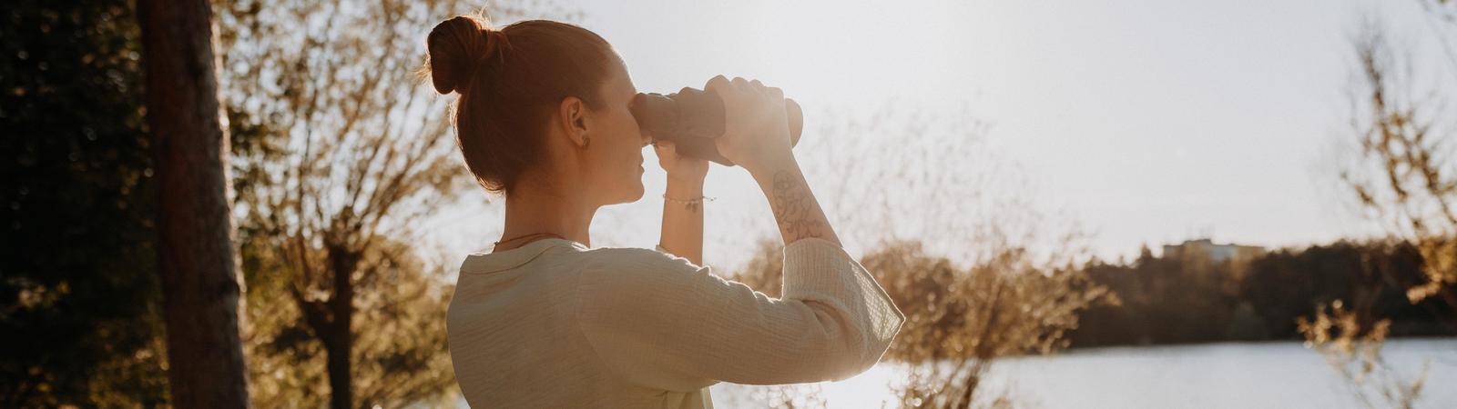 Frau mit Fernglas am See