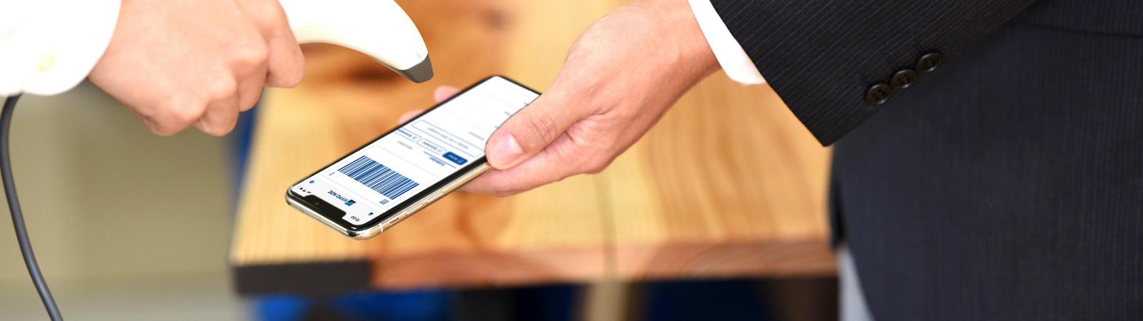 ein Mann hält ein Smartphone zu einem Barcode-Scanner