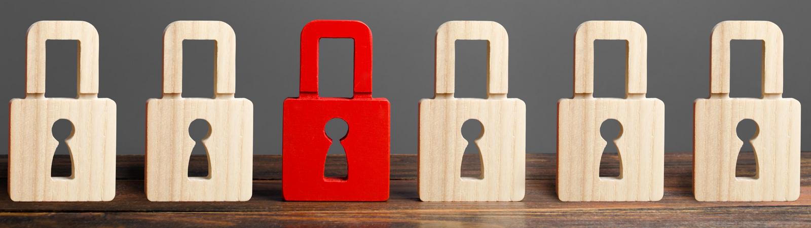 Rotes Vorhängeschloss unter weiteren beigefarbenen Vorhängeschlössern