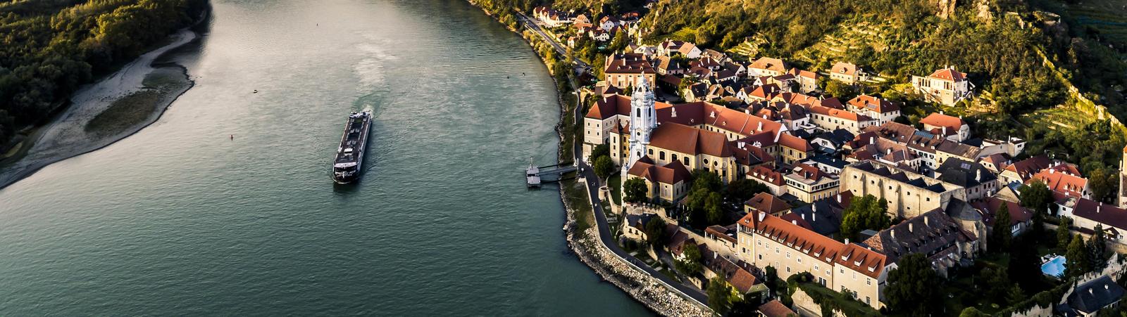 Blick auf den Fluss Donau mit Boot und das Tal Wachau mit dem Dorf Dürnstein im Vordergrund