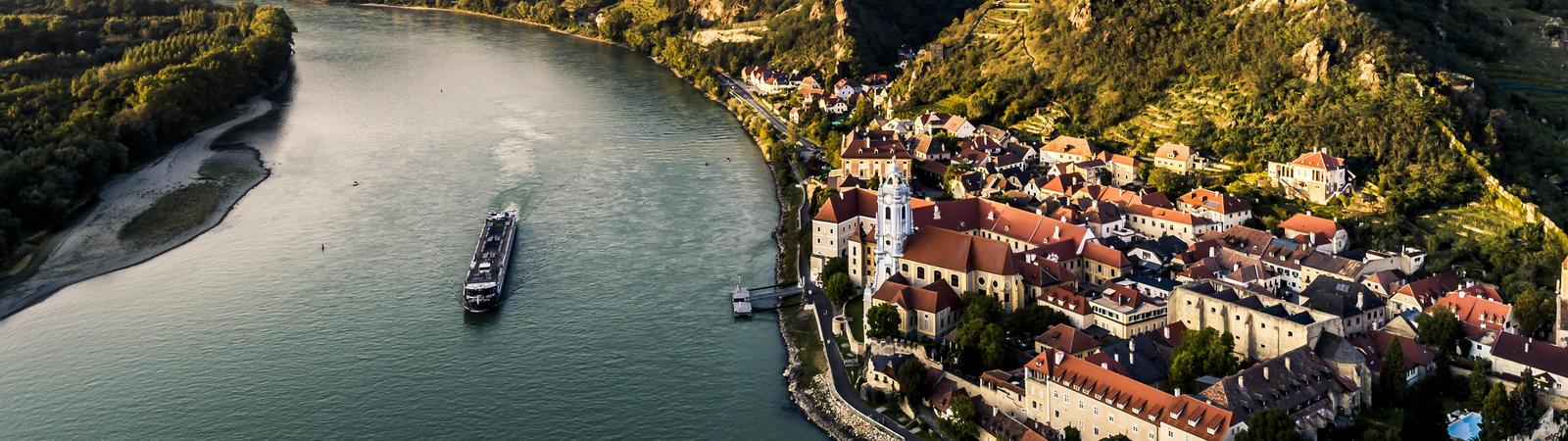 Blick auf den Fluss Donau mit Boot und das Tal Wachau mit dem Dorf Dürnstein im Vordergrund
