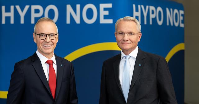 Zwei Männer mittleren Alters im Anzug stehen vor einem dunklen Hintergrund mit Aufschrift "HYPO NOE".
