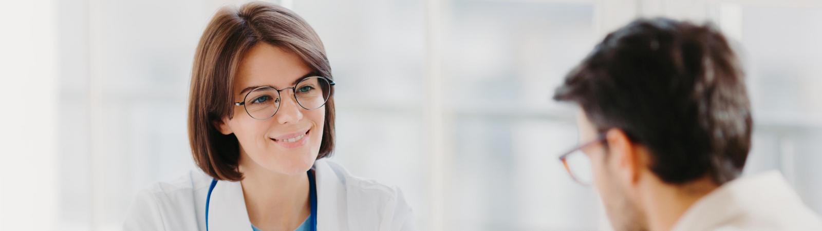 Junge Ärztin unterhält sich mit Patient