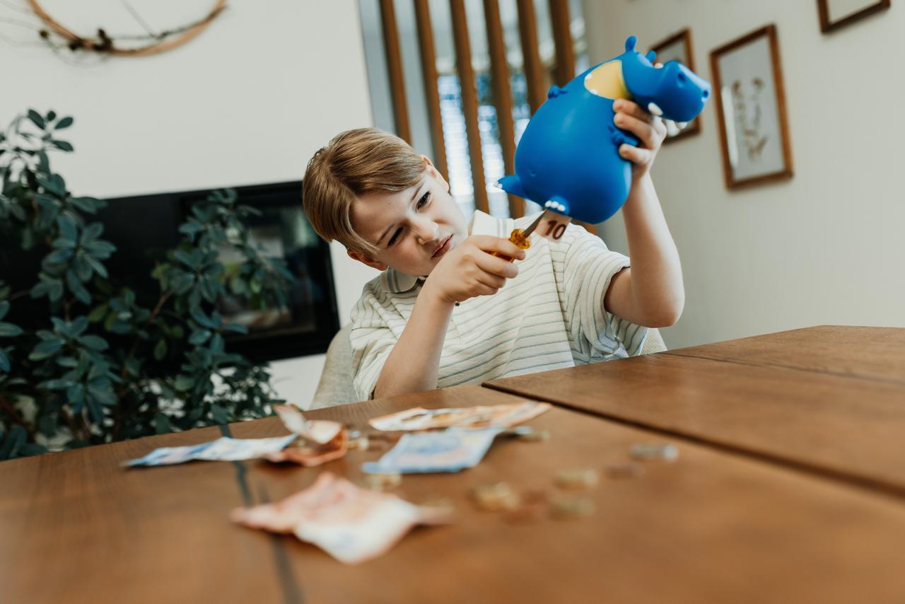 Weltspartag Kind fischt Geld aus Hippospardose